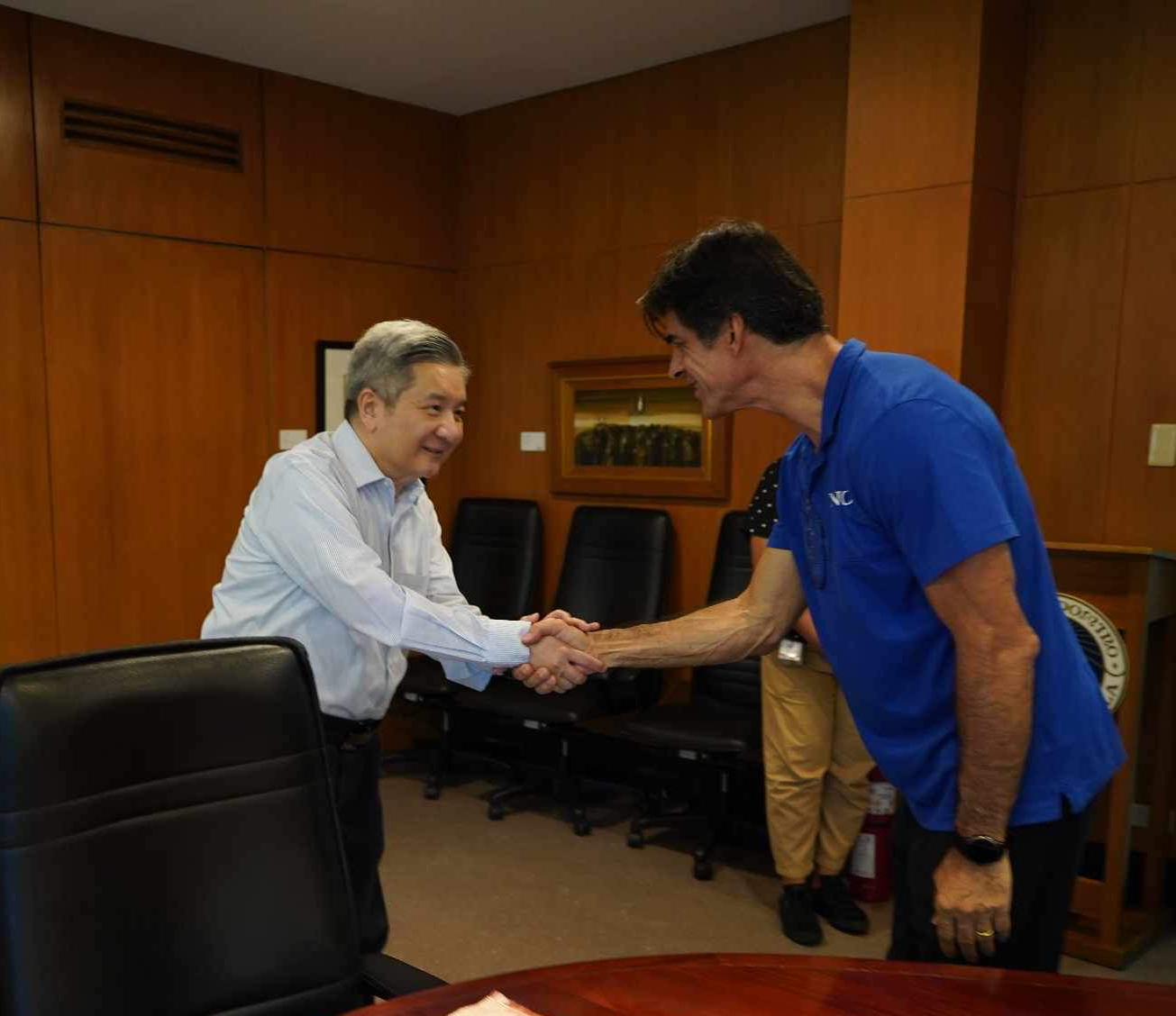 Fr. Bobby Yap shakes hands with Coach Sergio Veloso of the Women's Volleyball Team