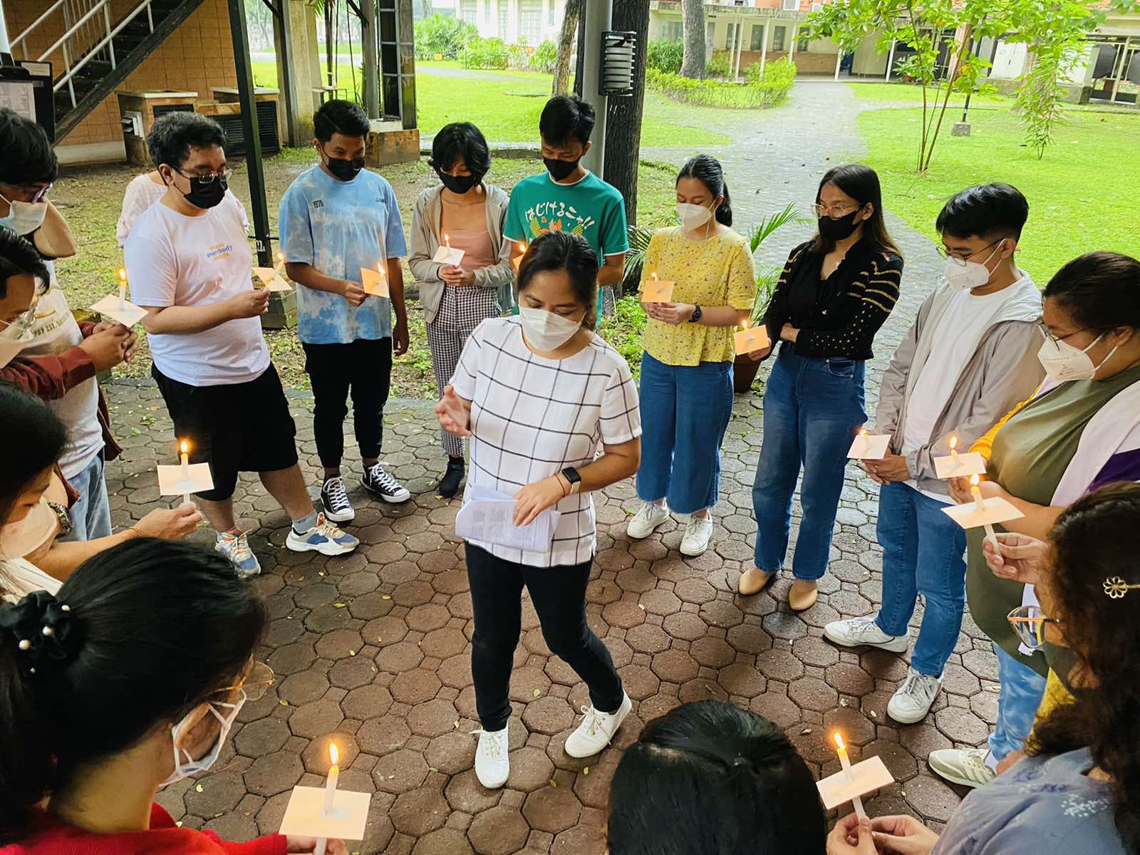Scholars gather in a circle, lighting candles.