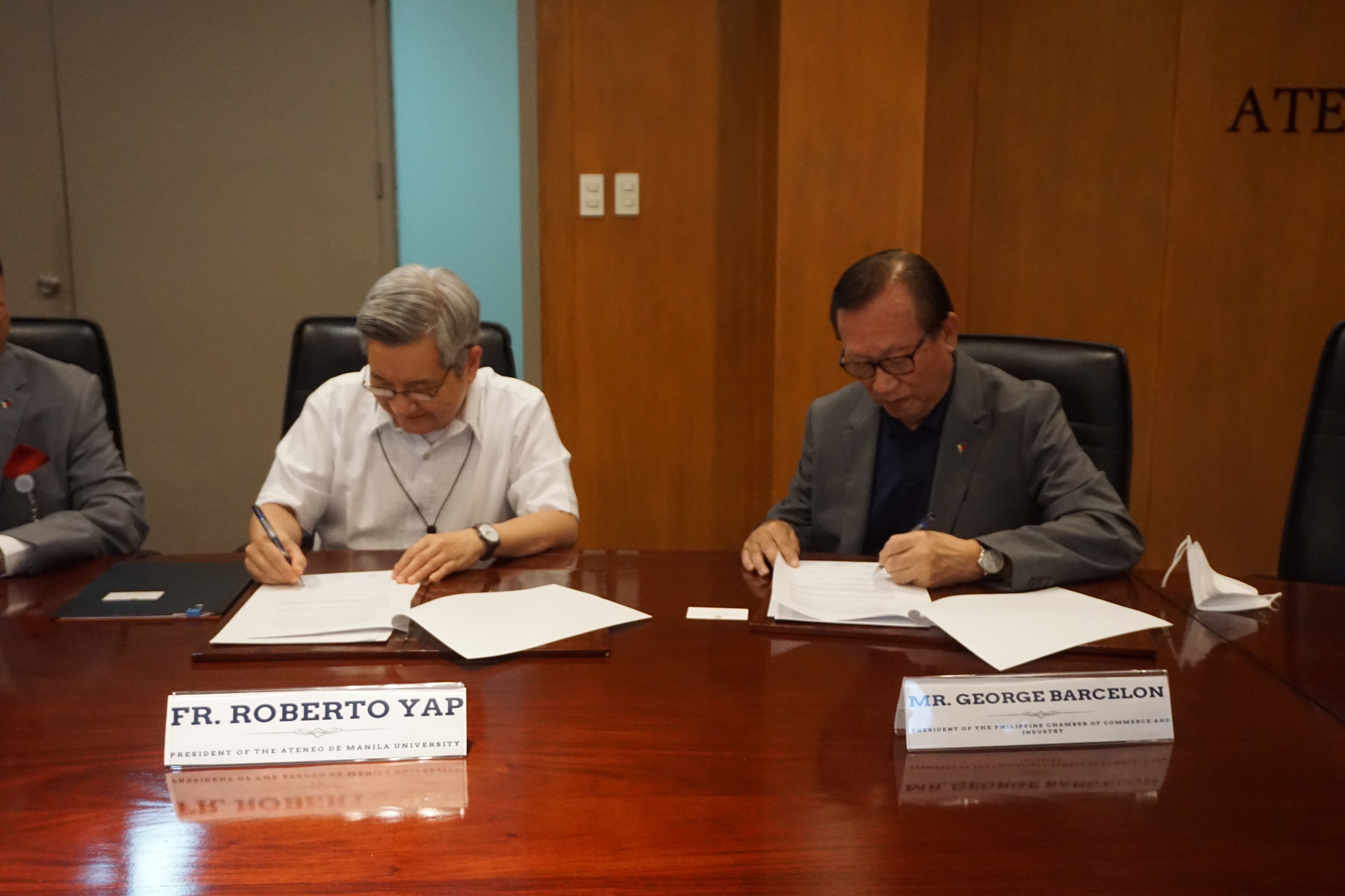 Fr Yap and Mr Barcelon signing the MOA