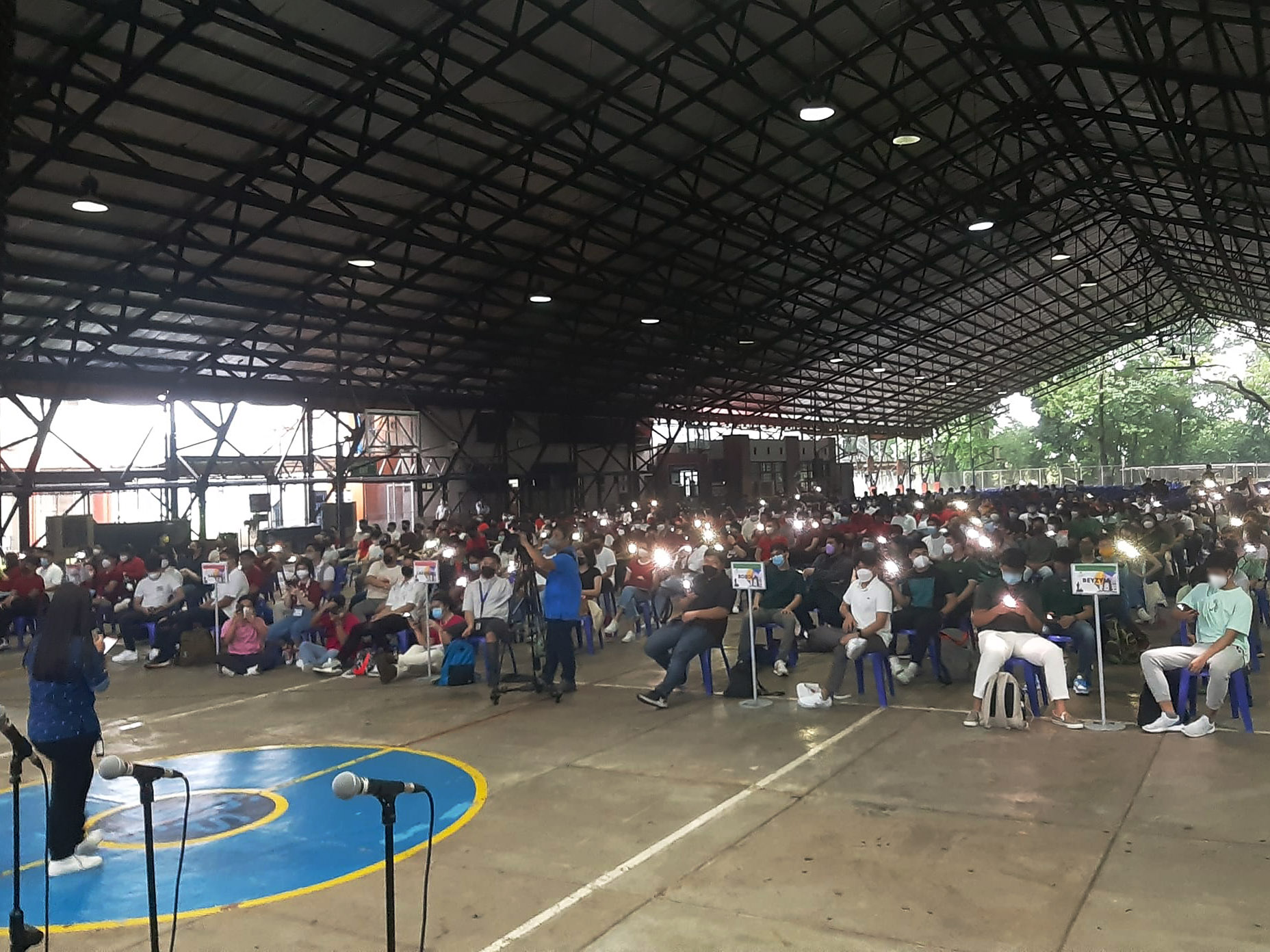 Grade 12 students light up their cellphones for ACO moderator Ms. Marydel Alaba (left)