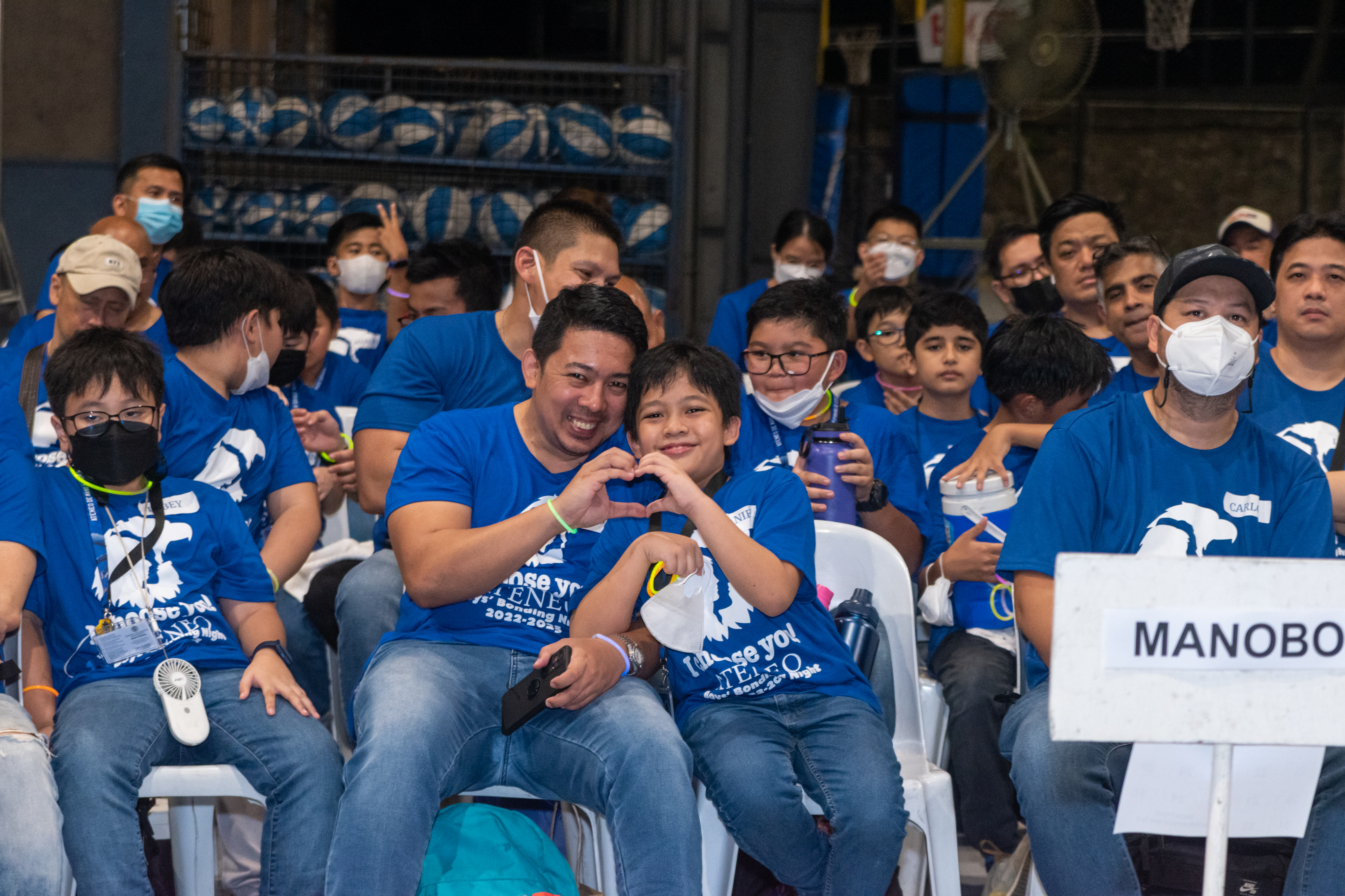 A hand heart - like the emoji- is a fun and playful way to express love and affection as shown here by this dad-and-son duo