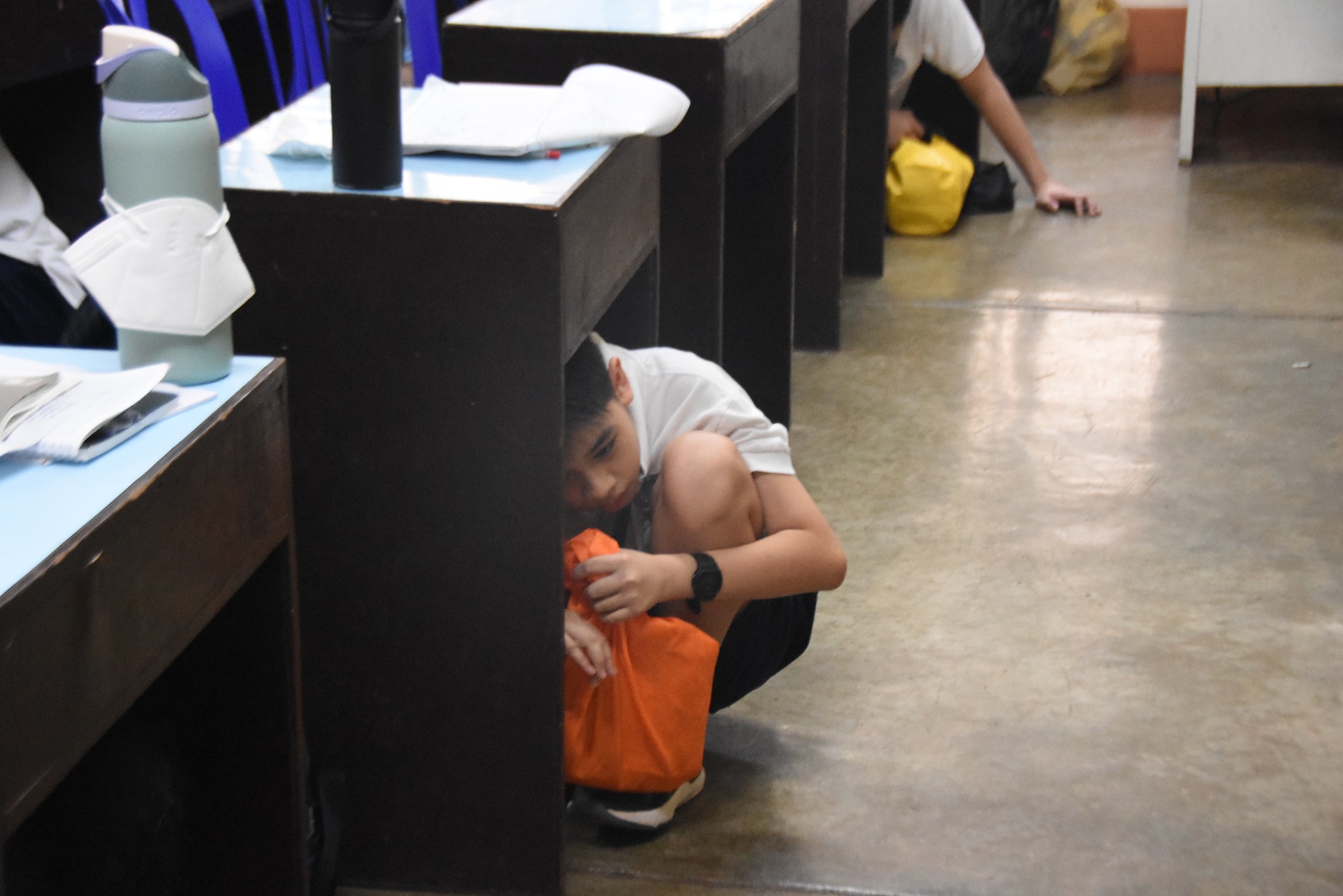 AJHS student ducks under the table during the unannounced drill drill 