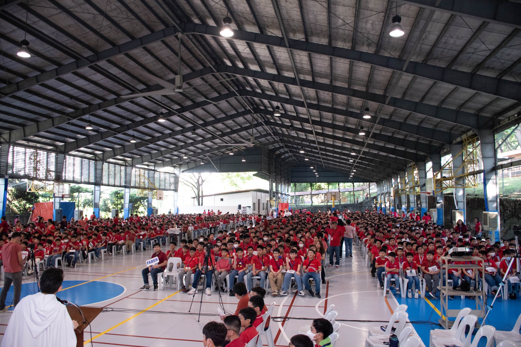The AGS celebrated its Votive Mass of the Holy Spirit – a.k.a. the Red Mass – in the AGS Covered Courts this morning. The celebration was the first large community gathering of the new school year, and was attended by administrators, teachers, workers, and students from Grades 3, 4, 5, and 6. The presider/homilist was Vice President for Basic Education Fr Jonjee Sumpaico SJ. Concelebrating with him were AGS Chaplain Fr Vic de Jesus SJ, AJHS Chaplain Fr Mamert Mañus SJ, and Ateneo College Chaplain Fr Munching de Guzman SJ.     The Red Mass is a Jesuit school tradition during which the community gathers to thank the Holy Spirit for His gifts (wisdom, understanding, counsel, fortitude, knowledge, piety, and fear of the Lord), and to seek His guidance and wisdom during the coming academic year. The Red Mass is named as such because the color red symbolizes the “tongues of fire” that descended on the apostles during Pentecost and filled them with the Holy Spirit (Acts 2:1-4). In his homily, Fr Jonjee shared that since much has been given to us by God through the seven gifts of the Holy Spirit, much is also expected of us. He explained that since the effects of these gifts are external growth and growth within, we should therefore be moved to express our gratitude for these gifts by sharing them with others and serving others. “Finding our minds more ready and open, finding our hearts more loving, and our hands being able to give more service to God, to others, and to our very selves... (would result in) a grace-filled year filled with life and confidence …in a God who continues to remind us that we are much loved,” Fr Jonjee emphasized.  Later in the Mass, a Prayer of Blessing for Students was also held during which the priest celebrants went around the covered courts sprinkling the students with holy water as a reminder of their Baptism, when they first received the Spirit of God. Just before the celebration ended, the Rite of Commissioning of AGS teachers, administrators, and workers took place, which had the format