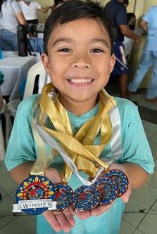 Luc Lopez with a clutch of medals, including one of his four "Most Outstanding Swimmer" awards 