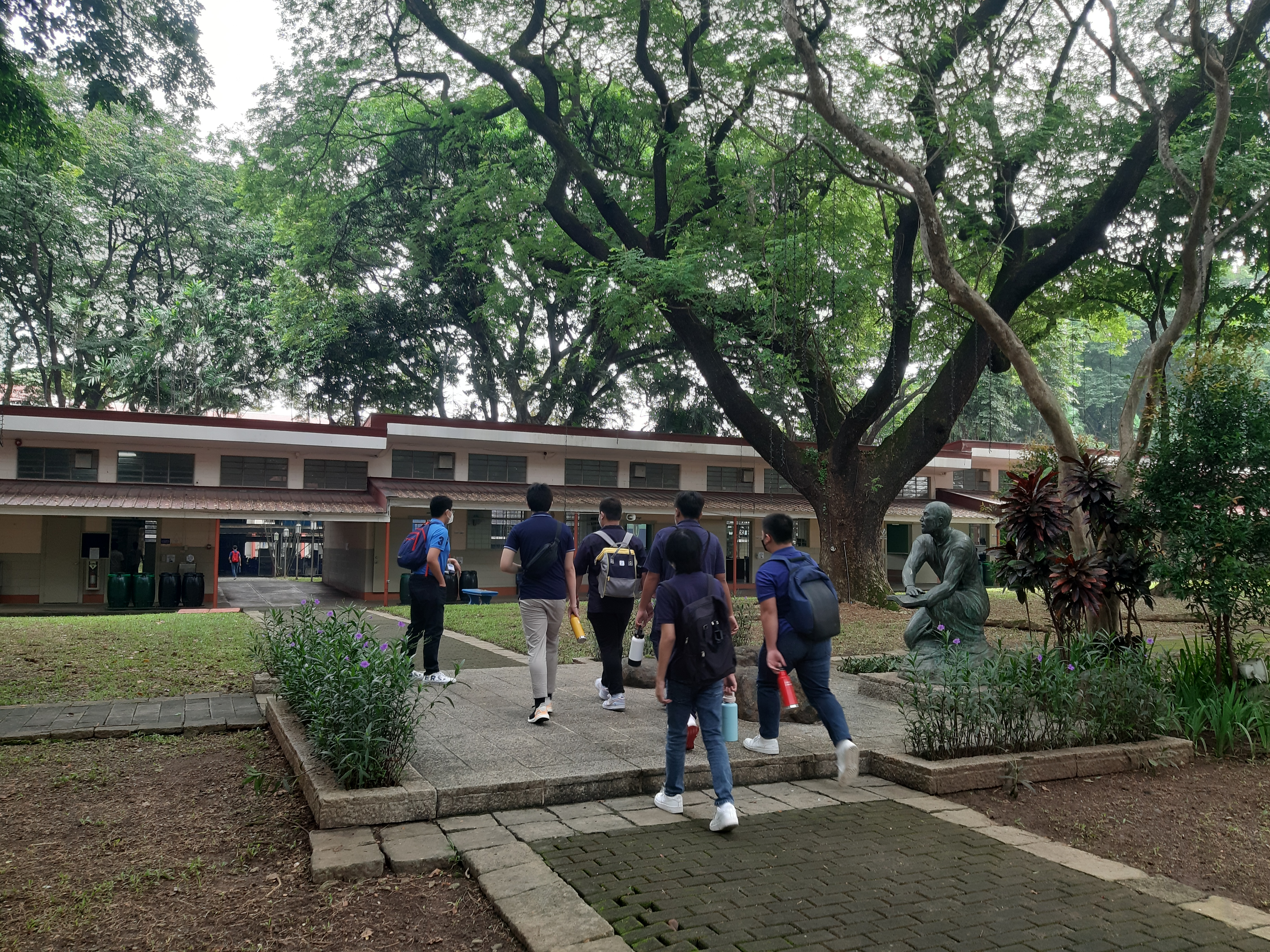 Students pass by the statue of St. Ignatius on their way to the covered courts
