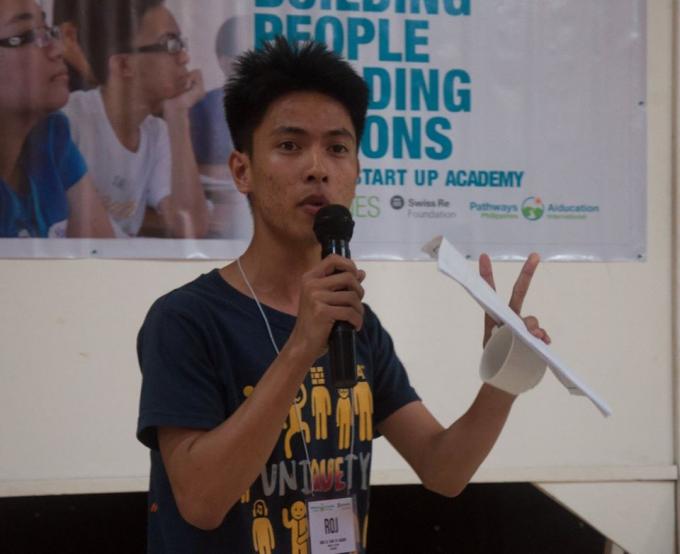 A young student presents his ideas with a microphone in hand.