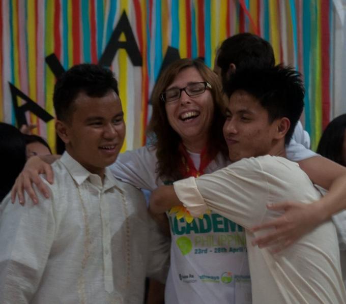 A student in a barong and a student in the event t-shirt hug their mentor.