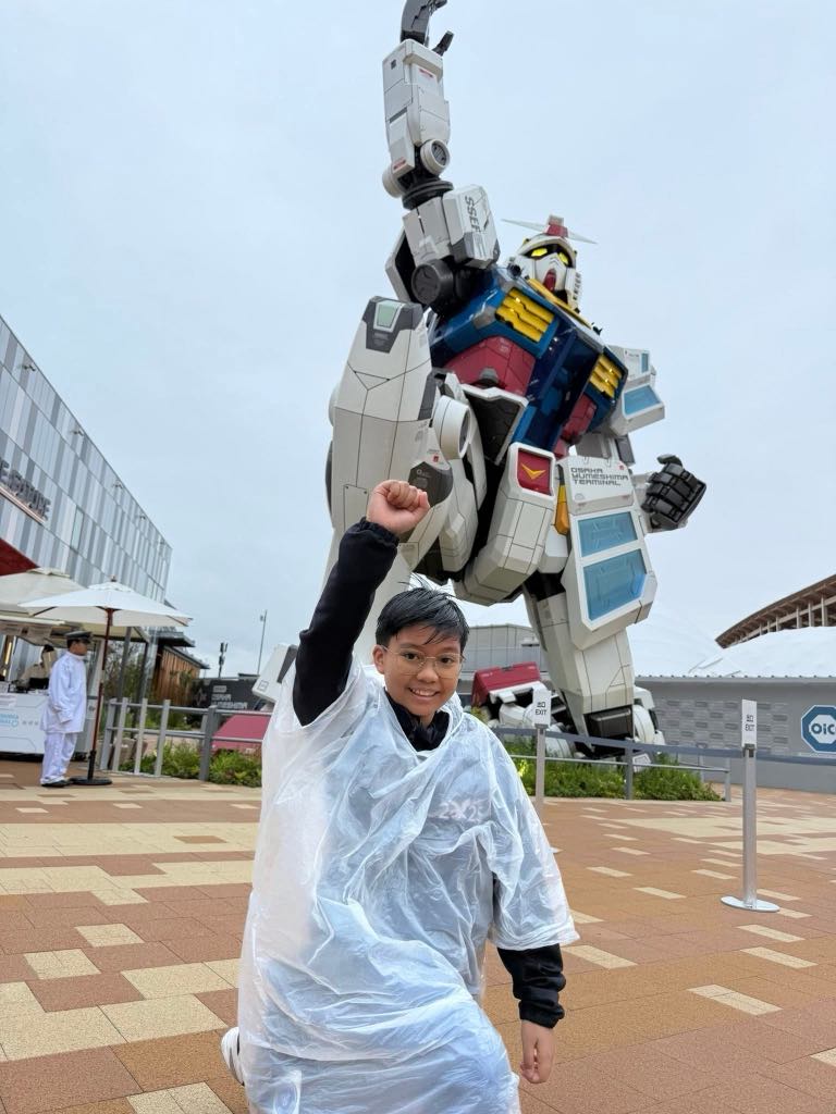 Austin Saulong poses with the life-sized Gundam statue at the Osaka Expo 2025