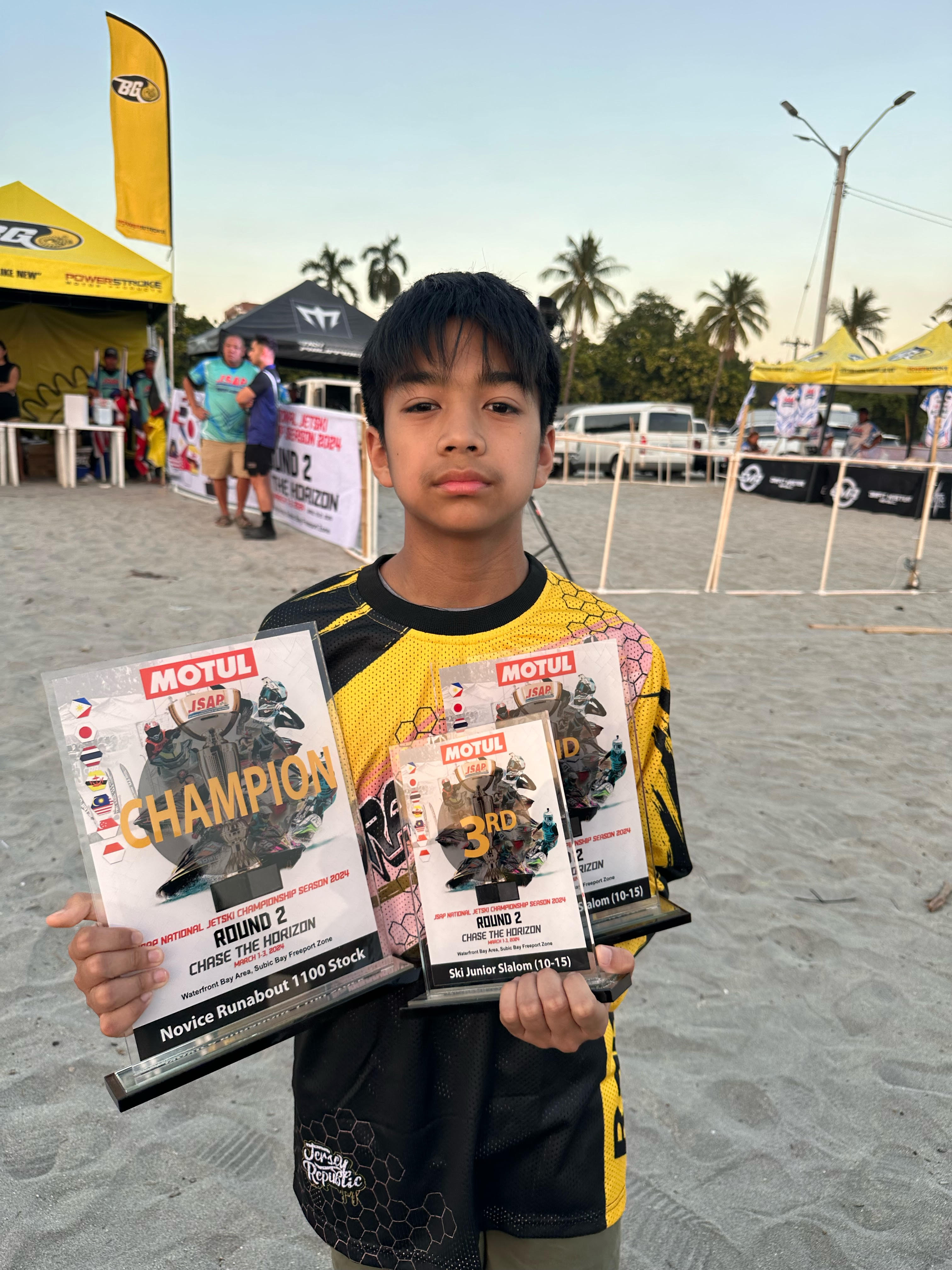 Vito Tinio holding his three trophies 