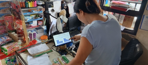 A micro-retailer examines store performance charts on a tablet, using insights from Packworks’ AI-supported reporting tool to guide daily business decisions.