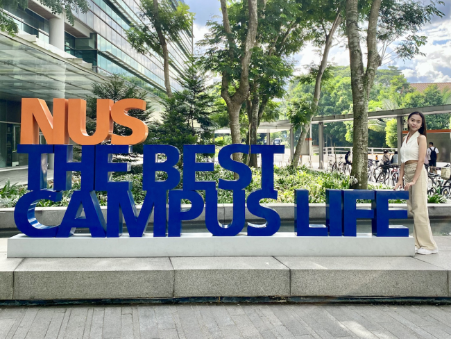 Elgene poses with the sign that says "NUS The Best Campus Life"