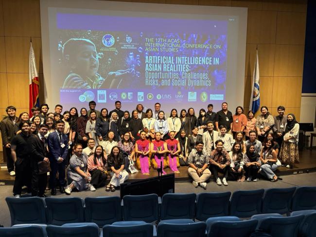Group photo of the conference attendees on stage, with the cultural performers from the Malaysian Embassy, taken after the closing program.