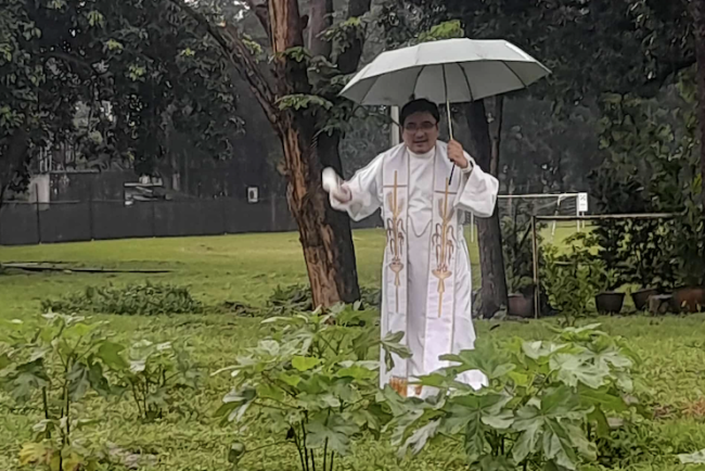 Fr Weng Bava SJ blesses the garden as rain falls 