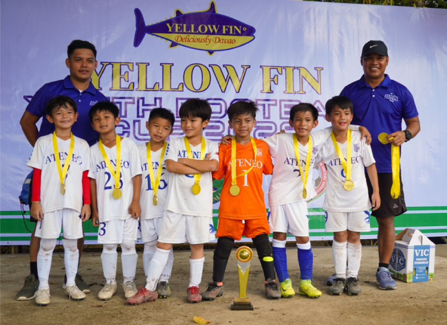 On Day 2, the Blue Eagles were crowned U7 Division Champions of the Yellow Fin Youth Football Cup 2025. Front row from left: Sage Kim, Ram Victoriano, Blaze Gonzales, Bastian Verzosa, Nathan Garcia, Gavin Windsor, Jaeden See; behind them from left: Coach Aldous Mirafuentes III, Coach Aldous Mirafuentes
